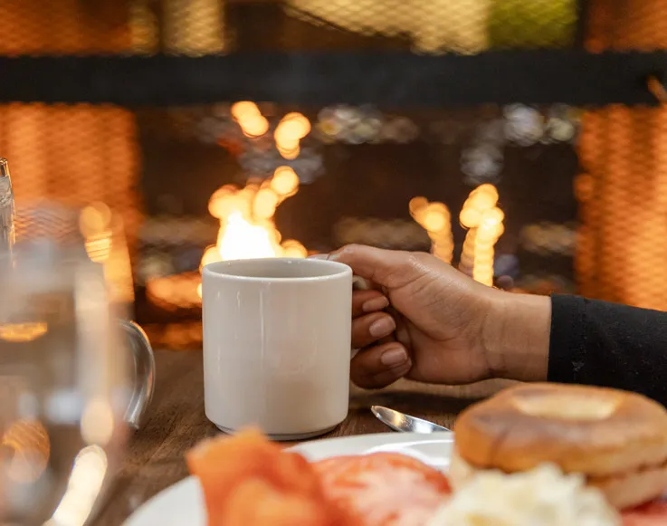 Upcoming Events 2 A hand holding a mug of coffee with breakfast foods in Jackalope's Bar & Grill
