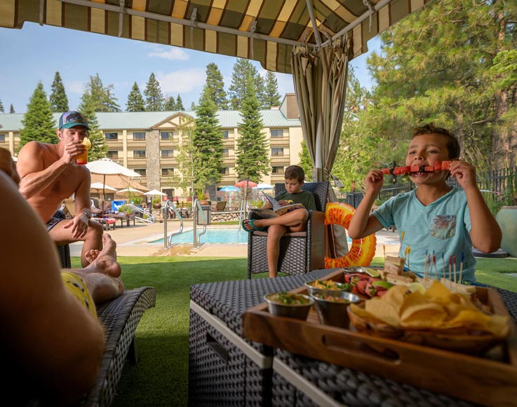 A family relaxing in a poolside cabana at Tenaya Lodge