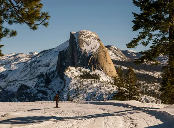 A winter skier in Yosemite National Park with Half Dome in the background