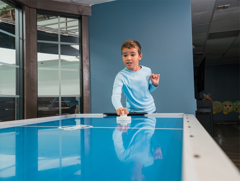 A boy playing air hockey in the game room at Tenaya at Yosemite