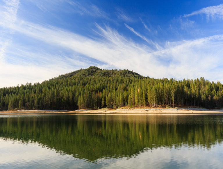 A tree covered mountain reflected in a lake