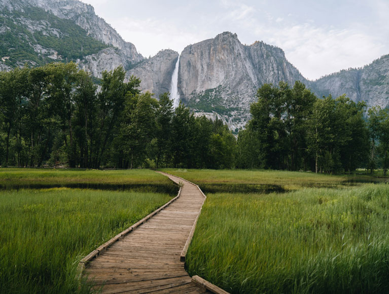 A meadow and boardwalk below Yosemite Falls