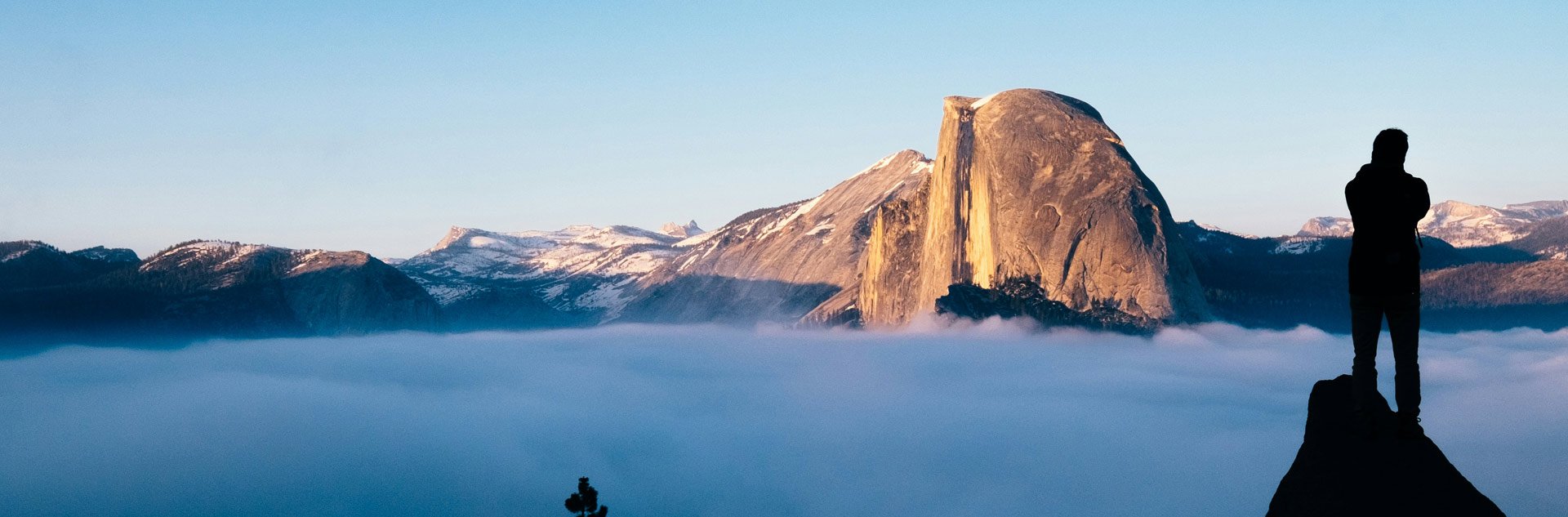 A Yosemite hiker admiring a view of Half Dome over a sea of clouds
