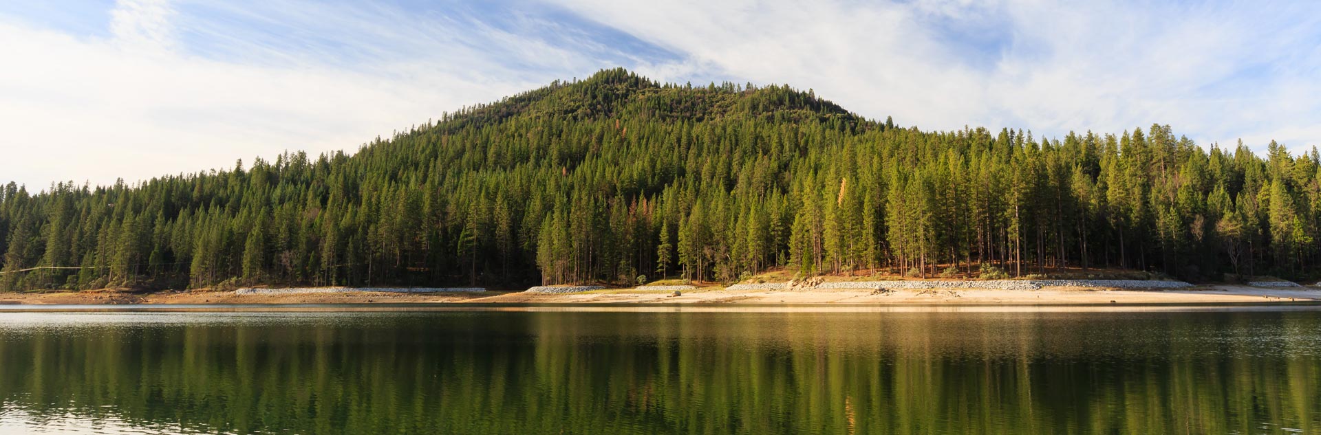 A tree covered mountain reflected in a lake