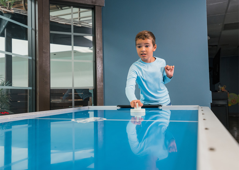 Home 8 A boy playing air hockey in the game room at Tenaya at Yosemite