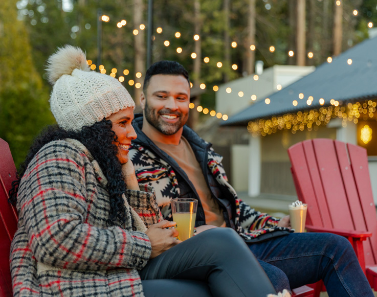 Two guests enjoying drinks by the fire at Tenaya at Yosemite
