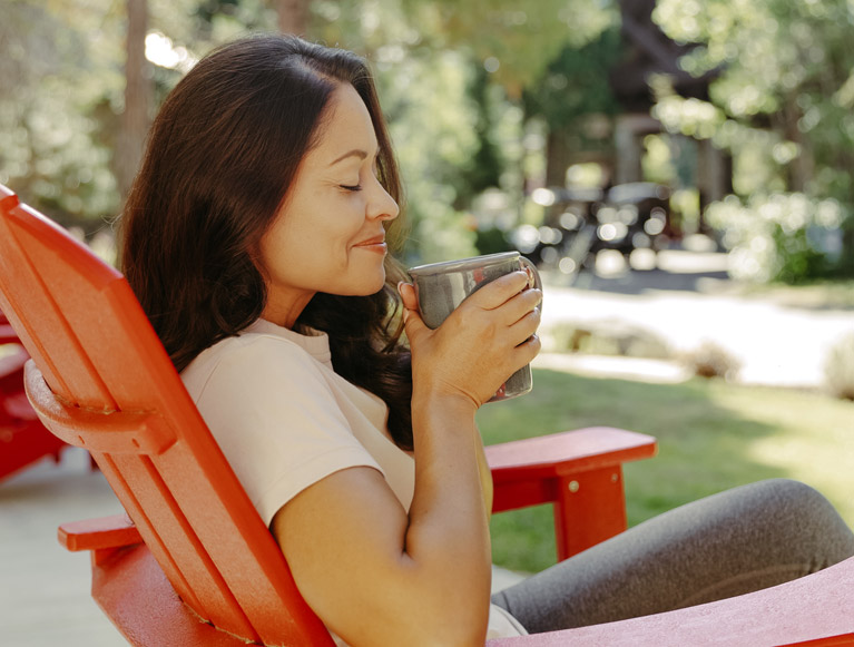 A Tenaya at Yosemite guest enjoying a beverage in an Adirondack chair