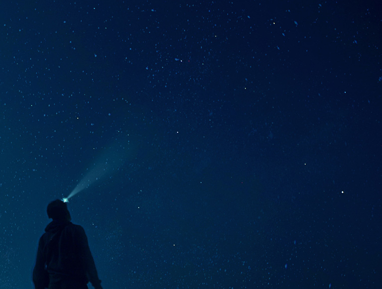 A guest with a headlamp looking up at the night sky