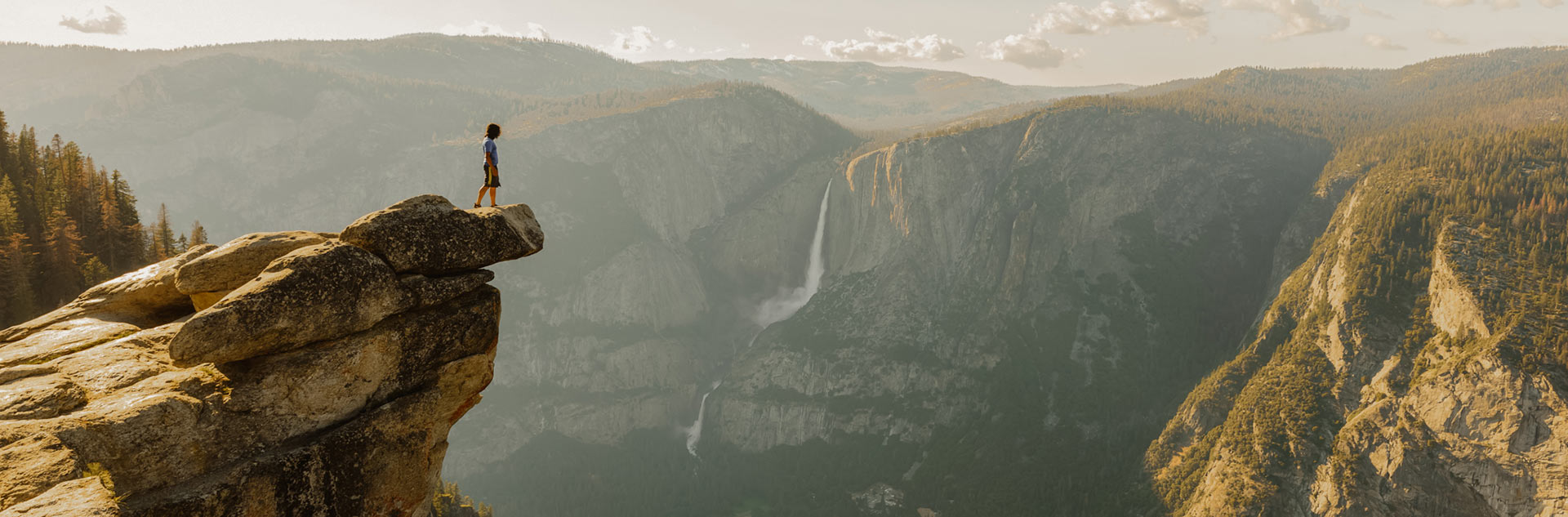 A hiker standing on a rocky outcropping over Yosemite Valley